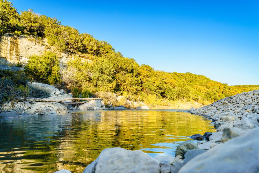 Scenic view of the Paluxy River at Dinosaur Valley State Park with golden sunlight reflecting on the water