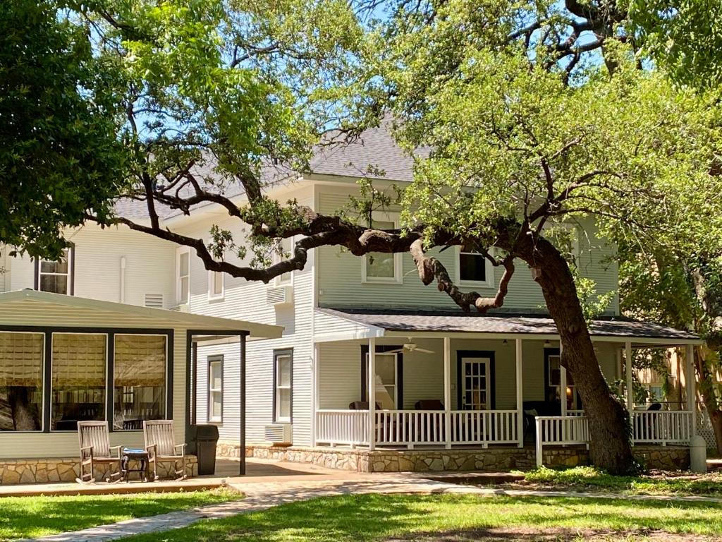 Inn on the River - Historic white and green building with large live oak trees and welcoming porches in Glen Rose, Texas