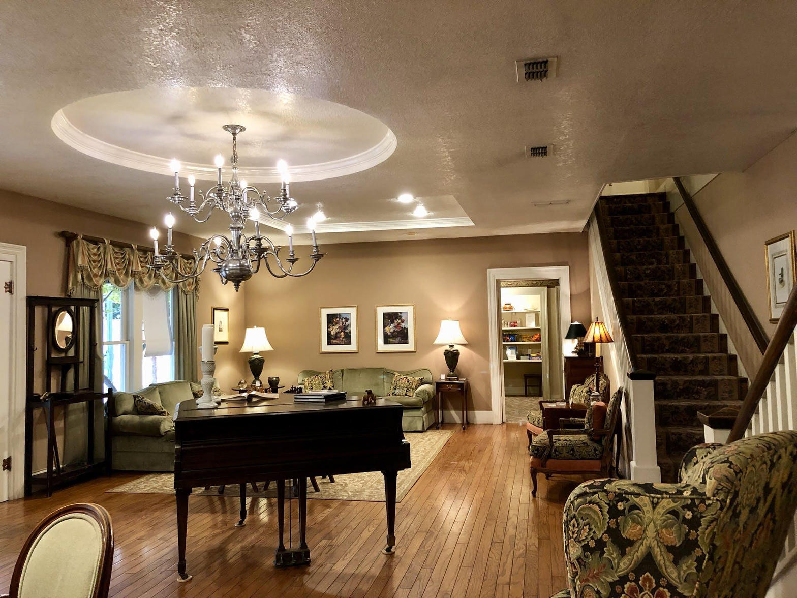 Elegant interior of the Inn on the River featuring a grand piano, crystal chandelier, and warm historic furnishings