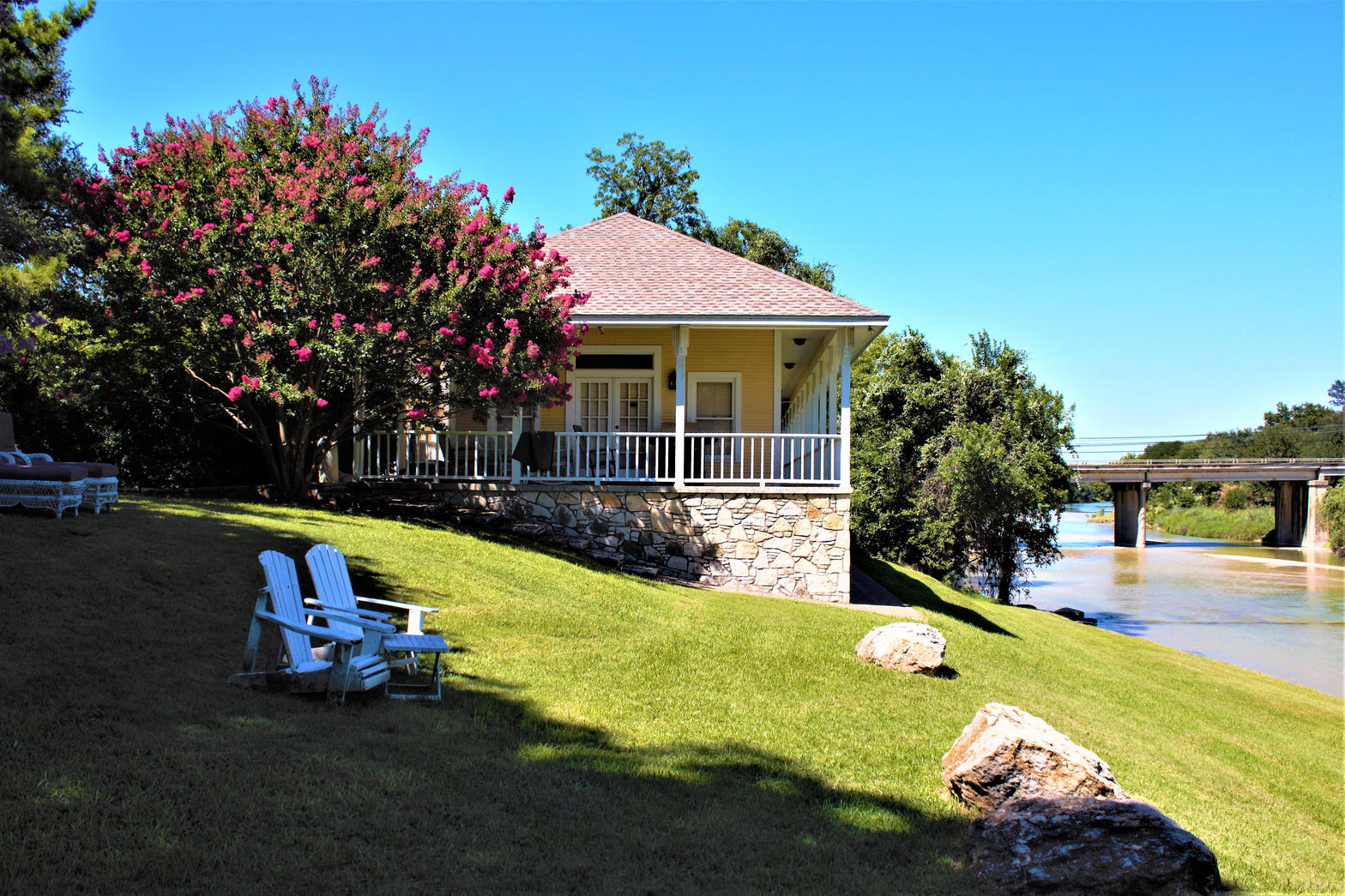 Inn on the River yellow historic building overlooking the Paluxy River with a bridge in the background